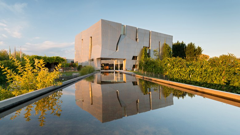 Loisium WeinWelt, © Loisium WeinWelt Modernes Gebäude der Loisium WeinWelt mit reflektierendem Wasserbecken im Vordergrund.
