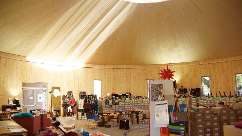 Werksverkauf in Holzjurte, © GEA Waldviertel Innenansicht einer Holzjurte mit Verkaufsständen und Sonnenstrahlen durch das Dachfenster.