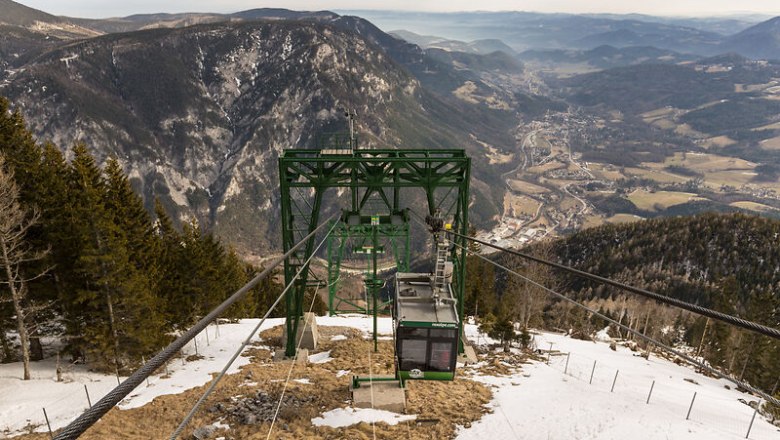 Rax-Seilbahn, © Martin Fülöp/NÖ-BBG Die Raxseilbahn schwebt majestätisch über die schneebedeckten Hänge, während die atemberaubende Berglandschaft sich unter ihr entfaltet. Hier, wo die frische Bergluft und die Ruhe der Natur aufeinandertreffen, wird jeder Moment zu einem unvergesslichen Erlebnis. Genießen Sie die spektakulären Ausblicke und die unberührte Schönheit der Alpen.