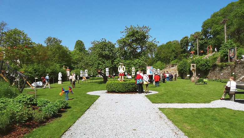 Karikaturengarten Brunn am Wald, © Gemeinde Lichtenau Besucher im Karikaturengarten Brunn am Wald, umgeben von Kunstwerken und grüner Landschaft.