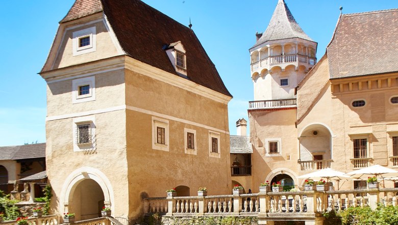 Rosenburg, © Lichtstark Historische Burg mit Türmen und Zinnen unter blauem Himmel.