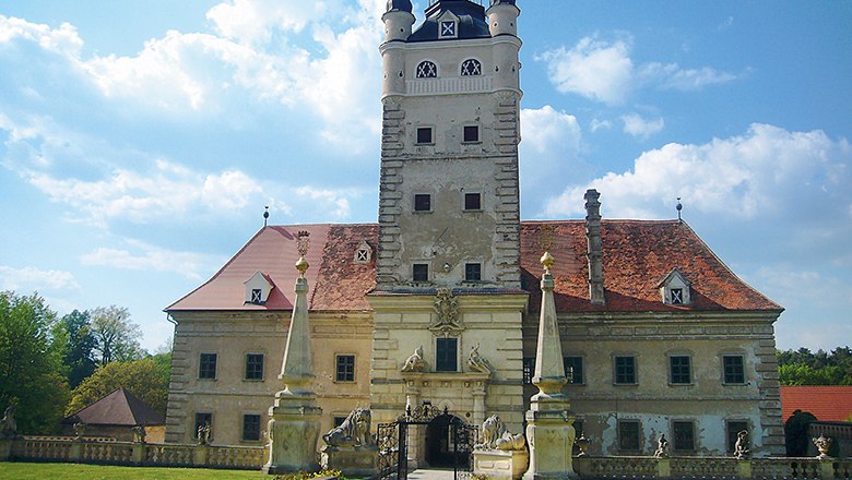 Schloss Greillenstein, © Schloss Greillenstein Schloss Greillenstein mit Turm und roten Dächern, umgeben von Statuen und einem Tor.