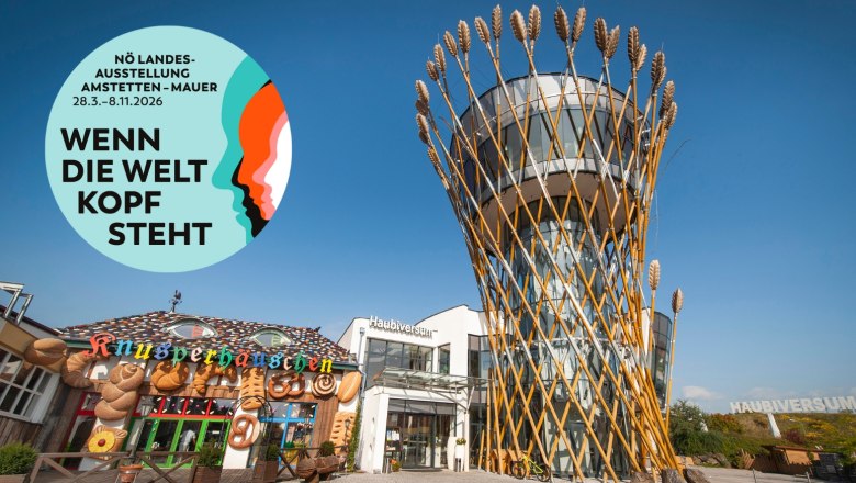 Haubiversum, © Haubis GmbH Gebäude mit Turm aus Weizenähren und Knusperhäuschen, Plakat für NÖ Landesausstellung 2026.