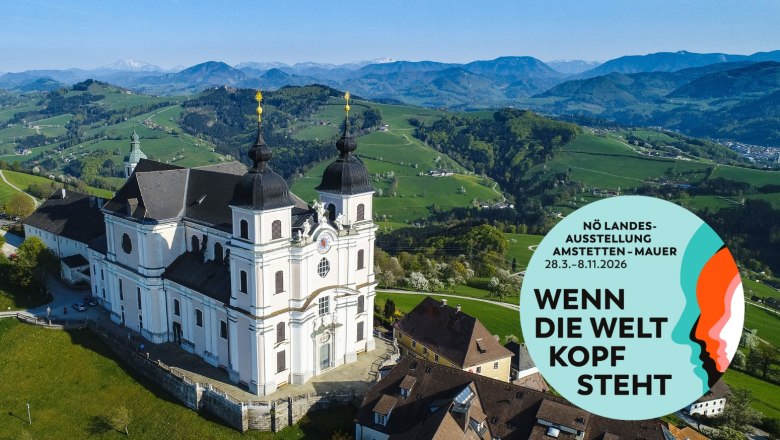 Basilika Sonntagberg, © Cleanhill Studios Luftaufnahme der Basilika Sonntagberg mit umliegender Landschaft und einem Werbeplakat für die NÖ Landesausstellung 2026.
