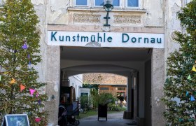 Eingang zur Kunstmühle Dornau mit dekorativen Elementen und Pflanzen.