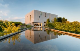 Modernes Gebäude der Loisium WeinWelt mit reflektierendem Wasserbecken im Vordergrund.