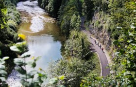 Radfahrer auf dem Ybbstalradweg entlang eines Flusses, umgeben von &uuml;ppiger Vegetation.