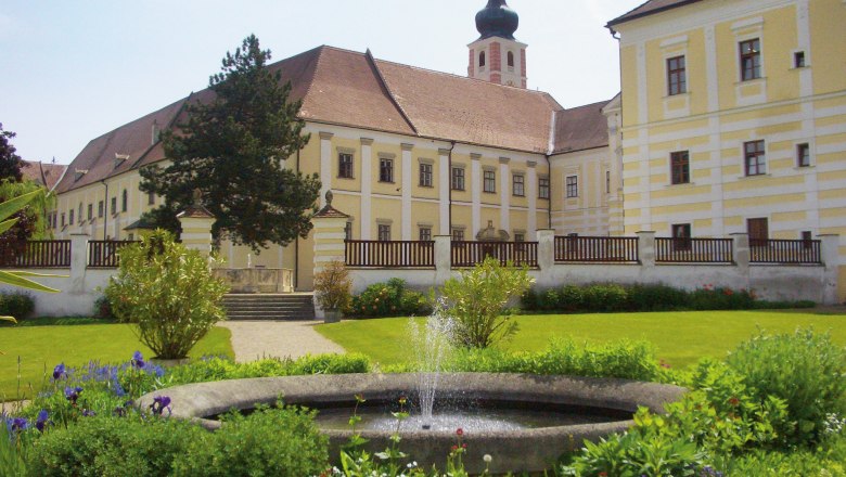 Historisches Klostergebäude mit Garten und Springbrunnen.
