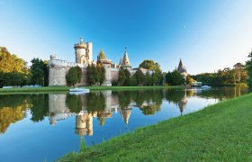 Franzensburg in Laxenburg, umgeben von Wasser und Bäumen, bei klarem Himmel.