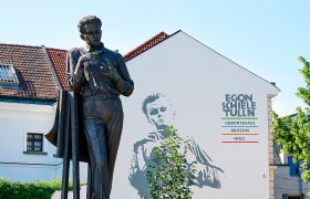 Statue vor dem Egon Schiele Museum in Tulln mit Wandbild im Hintergrund.
