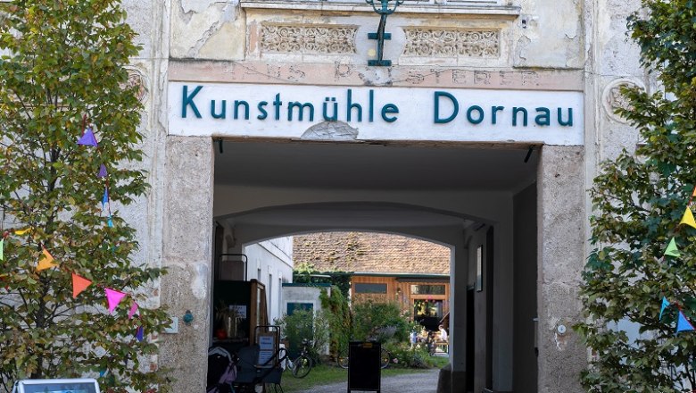 Eingang zur Kunstm&uuml;hle Dornau mit dekorativen Elementen und Pflanzen.