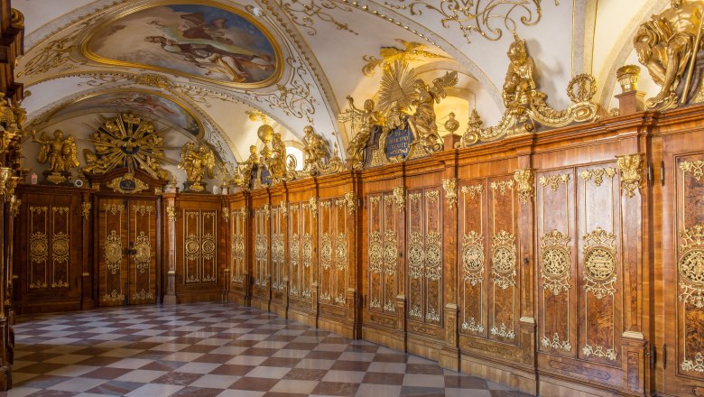 Prunkvoller Raum mit verzierten Holzpaneelen und Deckenmalerei.