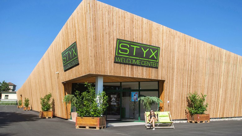 Modernes Gebäude mit Holzverkleidung und STYX Welcome Center Schild.