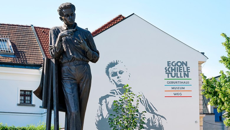 Statue vor dem Egon Schiele Museum in Tulln mit Wandbild im Hintergrund.