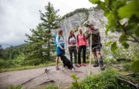 Gruppe von Wanderern mit Hund in bergiger Landschaft.
