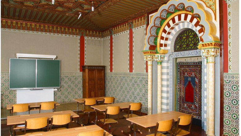 Ein klassenzimmer mit maurischem Dekor, bunten Fliesen und Holzmöbeln.