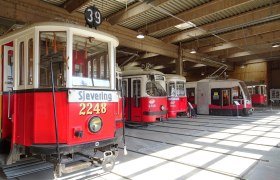Innenansicht eines Depots mit mehreren historischen Straßenbahnen in Traiskirchen.