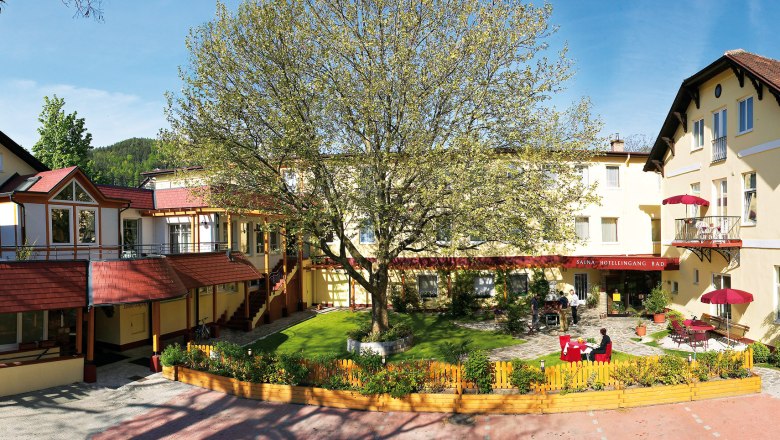 Außenansicht des Hotel Payerbacherhof mit großem Baum im Innenhof.