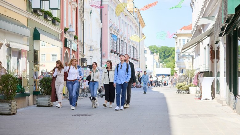 Gruppe von Menschen spaziert durch eine belebte Einkaufsstraße in St. Pölten.