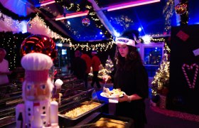 Stimmungsvoll beleuchtetes Winterevent bei Topgolf mit festlicher Dekoration, Weihnachtslichtern und Buffet in gem&uuml;tlicher Weihnachtsatmosph&auml;re.