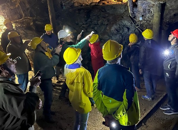 Gruppe von Menschen mit Helmen in einer beleuchteten Höhle.