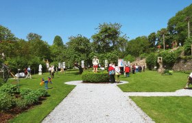 Besucher im Karikaturengarten Brunn am Wald, umgeben von Kunstwerken und grüner Landschaft.