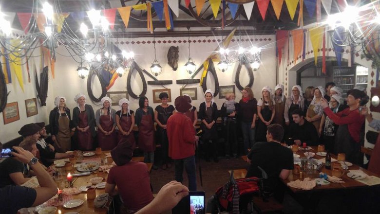 Menschen in mittelalterlicher Kleidung bei einem Festmahl in einem dekorierten Raum.