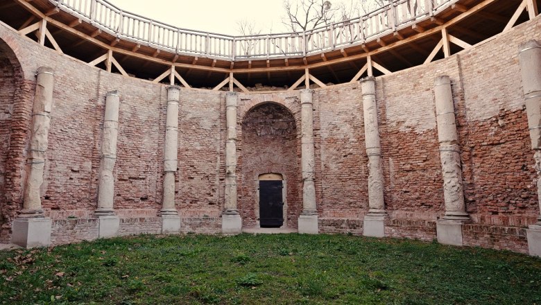 Innenhof mit Backsteinmauern und S&auml;ulen, umgeben von einem h&ouml;lzernen Gel&auml;nder.