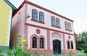 Ein rosa Gebäude mit römischen Zahlen und dekorativen Fenstern.