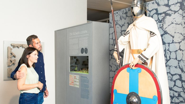 Ein Paar betrachtet eine römische Soldatenfigur im Stadtmuseum Tulln.