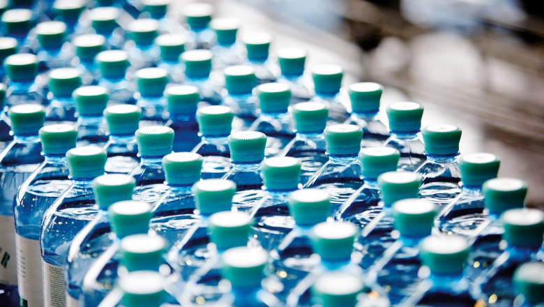 Reihen von V&ouml;slauer Mineralwasserflaschen mit gr&uuml;nen Verschl&uuml;ssen.