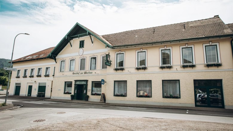 Ein traditionelles Gasthaus mit gelber Fassade und gr&uuml;nen Fensterl&auml;den, beschriftet mit 'Gasthof zur Wachau'.