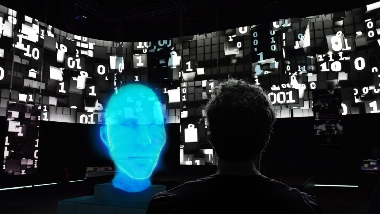 Ein Mensch betrachtet eine digitale Darstellung eines blauen Gesichts vor einem Hintergrund mit bin&auml;ren Zahlen.