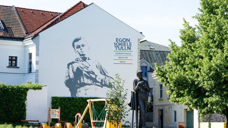 Außenansicht des Egon Schiele Museums in Tulln mit Wandbild und Statue.
