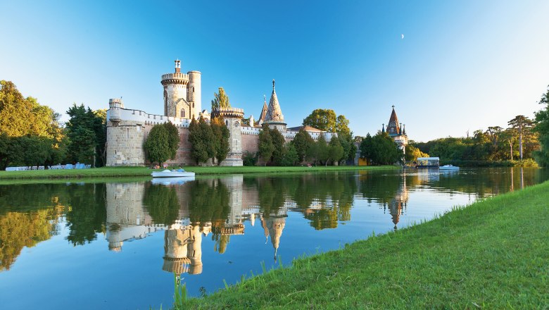 Franzensburg in Laxenburg, umgeben von Wasser und Bäumen, bei klarem Himmel.