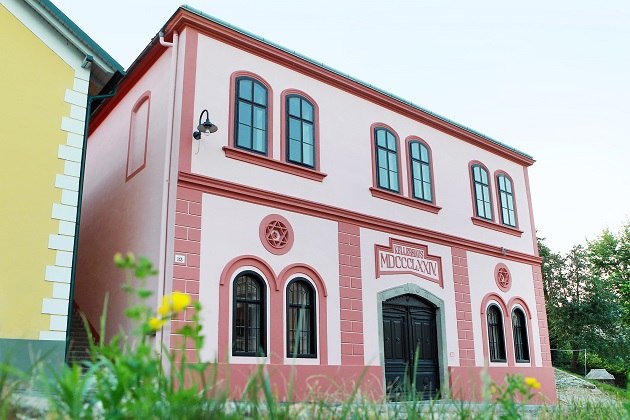 Ein rosa Gebäude mit römischen Zahlen und dekorativen Fenstern.