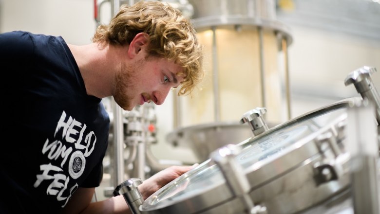 Ein Mann schaut in einen Braukessel in einer Brauerei.