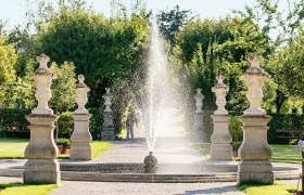 Springbrunnen im Garten des Stifts Seitenstetten mit Statuen und Bäumen im Hintergrund.