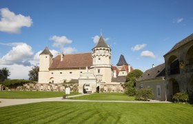 Schloss Rosenburg mit Türmen und gepflegtem Rasen unter blauem Himmel.
