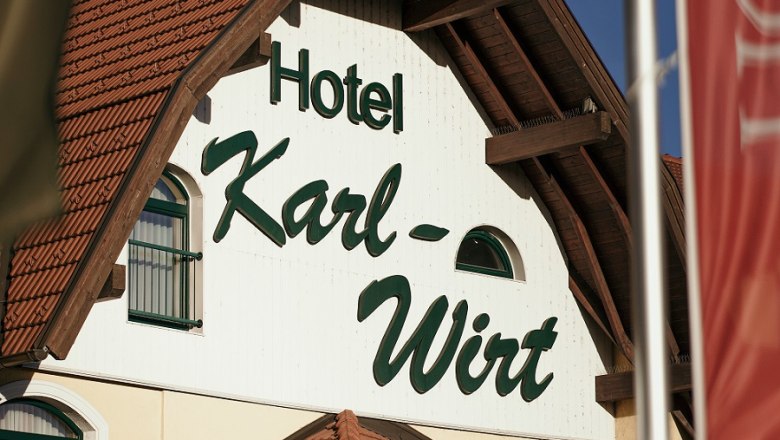 Fassade des Hotels Karl-Wirt mit rotem Dach und gr&uuml;nen Fensterl&auml;den.