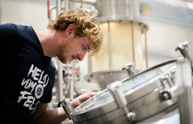 Ein Mann schaut in einen Braukessel in einer Brauerei.