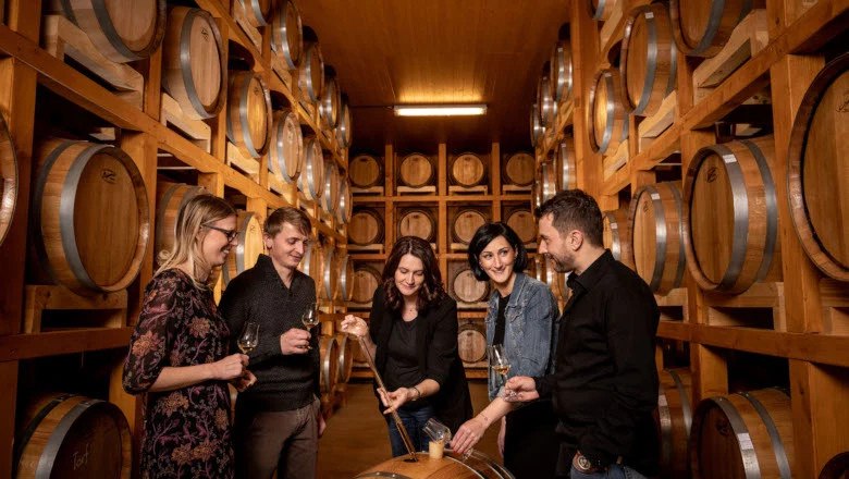 Gruppe von Menschen in einer Whisky-Destillerie, umgeben von Holzfässern.